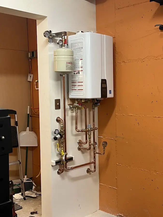 Plumbing technician inspecting water heater connections in Pitman